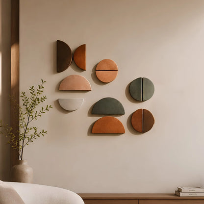A set of nine geometric wall art pieces in earthy tones of terracotta, sage green, charcoal, and cream, arranged on a beige wall in a styled interior setting with a vase of greenery and a wooden console.
